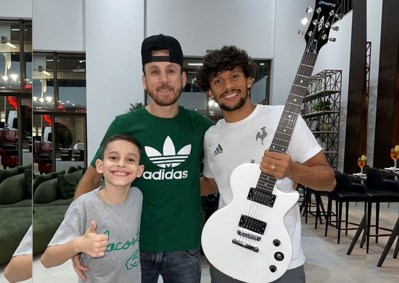 Gustavo Scarpa, meia do Atlético, ganhou a guitarra na chegada ao hotel em Cuiabá